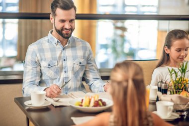 Çocuklar ve babaları restorandaki masada oturuyorlar.