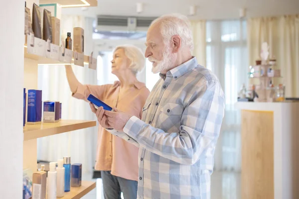 Pareja mayor eligiendo cosméticos en un salón de belleza — Foto de Stock