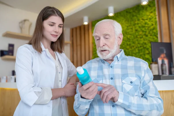 Ayudante de tienda ayudando a un anciano a elegir los productos para el cuidado del cuerpo —  Fotos de Stock