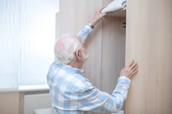 Gråhårig man i rutig skjorta som öppnar en garderob i ett omklädningsrum — Stockfoto