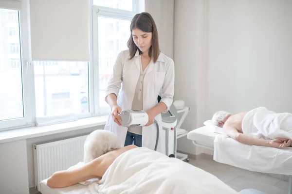 Joven fisioterapeuta haciendo rahabilitación masaje de espalda a pacientes de edad avanzada — Foto de Stock