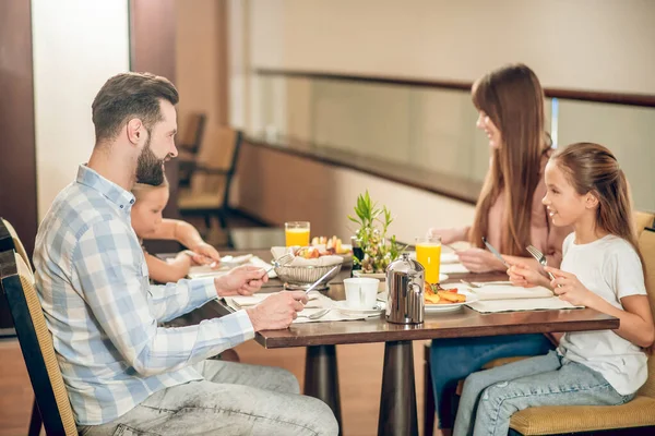 Young family sitting at the table in the restaurant — Stock Photo, Image