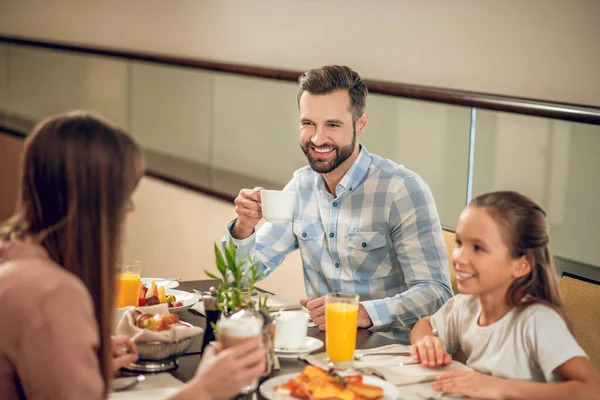 Baba kızıyla kahvaltı yapıyor ve mutlu görünüyor.