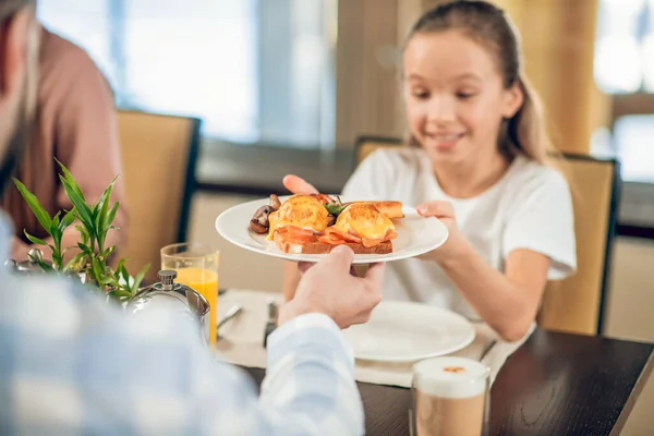 Mooi tiener meisje het nemen van een bord met eten van haar vaders handen — Stockfoto