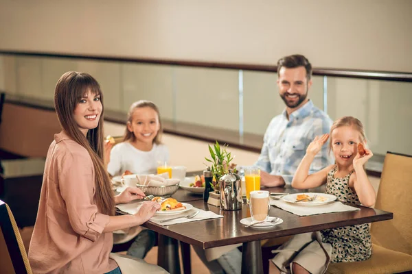 Усміхнена сім'я сидить за столом і виглядає щасливою — стокове фото