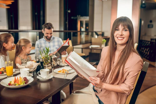 Elinde menü olan ve ne sipariş edeceğini seçen genç bir kadın. — Stok fotoğraf