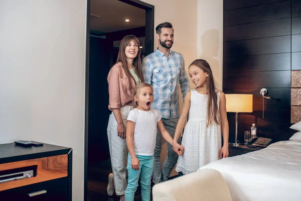 Молодая сладкая семья стоит в комнате и выглядит взволнованной — стоковое фото