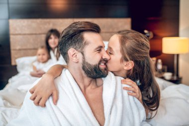 Sevimli bir kız babasına sarılıyor, ikisi de mutlu görünüyor.