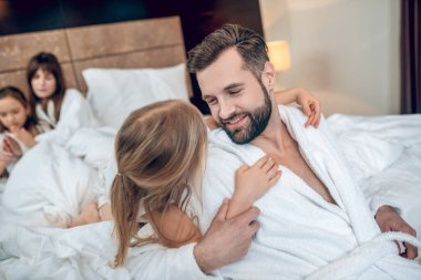 Genç sakallı adam kızıyla oynarken mutlu görünüyor.