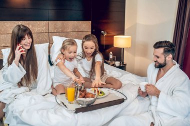 Çocuklar telefonda konuşurken oyun oynuyor, babalar kahve içiyor.