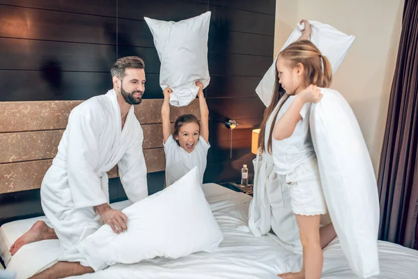 Rodzina w białych szatach walczy na poduszki — Zdjęcie stockowe