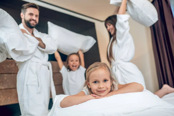 Семья в белых халатах сражается на подушках — стоковое фото