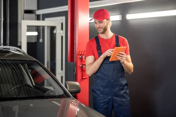 Man with tablet near car in workshop — Stock Photo, Image