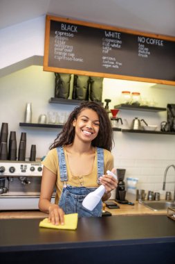 Kafede bar tezgahını silen güzel bir kadın.