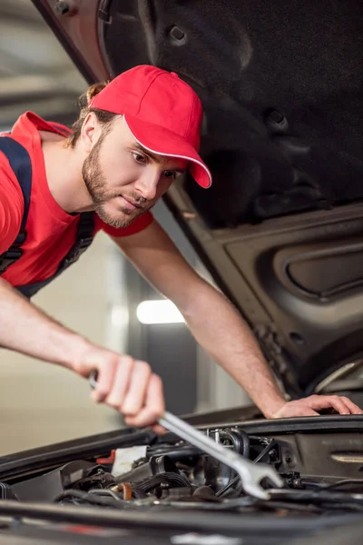 Man in overalls near hood repairing car — Stock Photo, Image