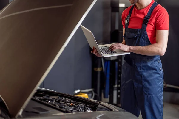 Auto mechanic hands with laptop near open hood — Stock Photo, Image