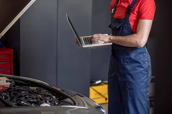 Male hands with laptop near car hood — Stock Photo, Image