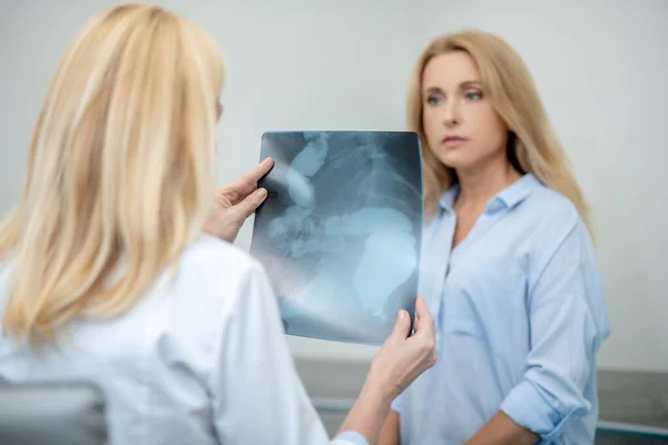 Médecin avec retour à la caméra montrant la radiographie au patient — Photo