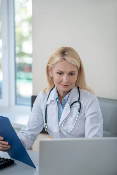 Mujer médico sentado en la oficina mirando el ordenador portátil — Foto de Stock