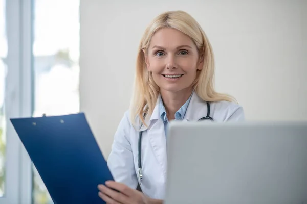 Femme heureuse médecin avec dossier au bureau — Photo