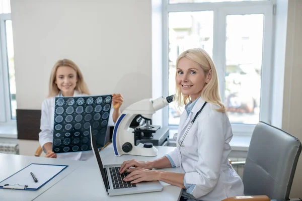 Kvinna läkare på laptop och kollega med MRT scan — Stockfoto