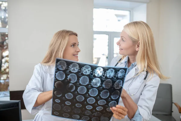 Dos mujeres con batas médicas con resonancia magnética hablando — Foto de Stock