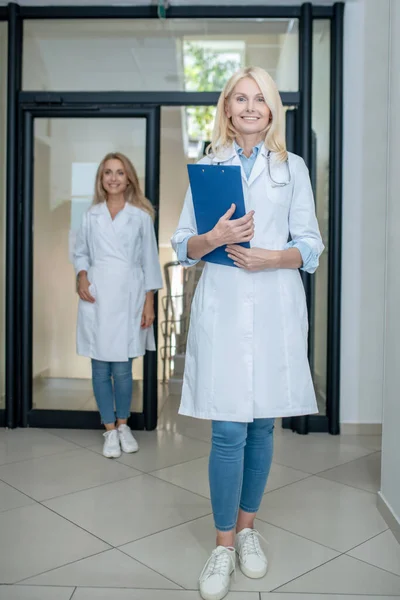 Női orvos sétál végig hall és kollégája mögött — Stock Fotó