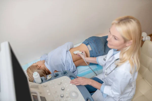 Внимательная женщина-врач, выполняющая ультразвуковое сканирование почки и пациента — стоковое фото