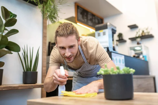 Hombre atento limpiando la superficie con concentración —  Fotos de Stock