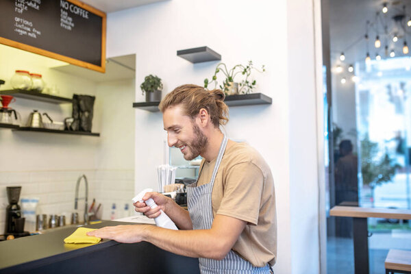 Long-haired man in profile cleaning up in cafe