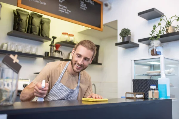 Smiling man carefully wiping surface of bar counter — Stock Photo, Image