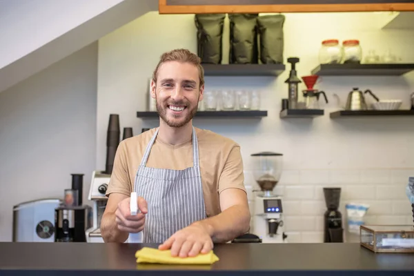 Gioioso giovane uomo barbuto pulire bancone del bar — Foto Stock