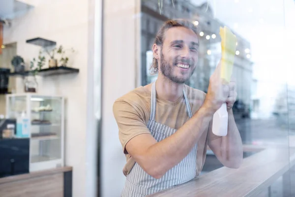 Hombre de pie detrás de vidrio en la superficie de limpieza de café —  Fotos de Stock