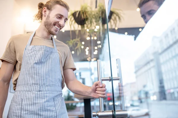 Mann steht neben Glastür und hält Türklinke — Stockfoto