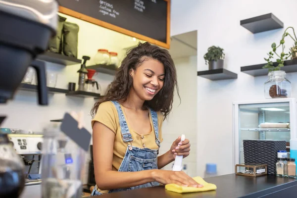 Betrokken lachende vrouw veegt de bar teller — Stockfoto