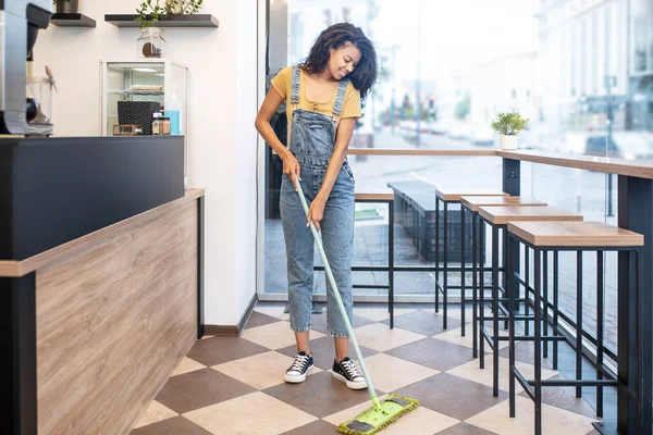 Mujer joven fregando piso en la cafetería — Foto de Stock