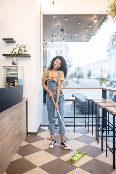 Mladá žena čištění kavárna v dobré náladě — Stock fotografie