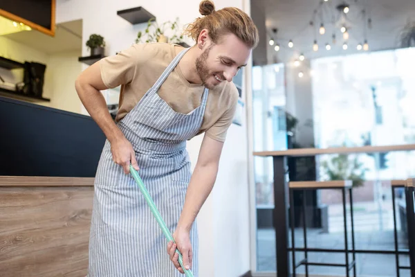 Fröhlicher Mann mit Wischmopp in der Nähe der Theke — Stockfoto