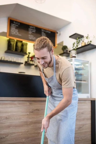 Mann in Schürze mit Wischmopp in Café — Stockfoto