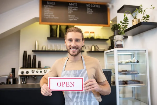 Homem satisfeito perto do balcão no café convidando visitantes — Fotografia de Stock