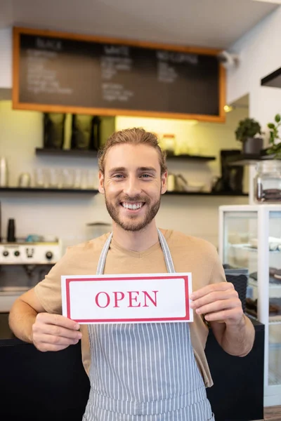 Homem otimista feliz segurando sinal Aberto no café — Fotografia de Stock