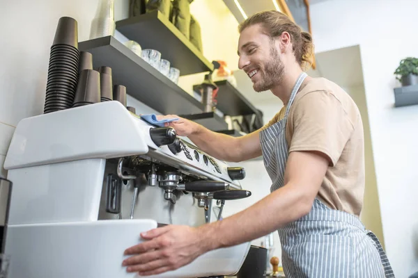 Homme joyeux dans tablier essuyant machine à café — Photo