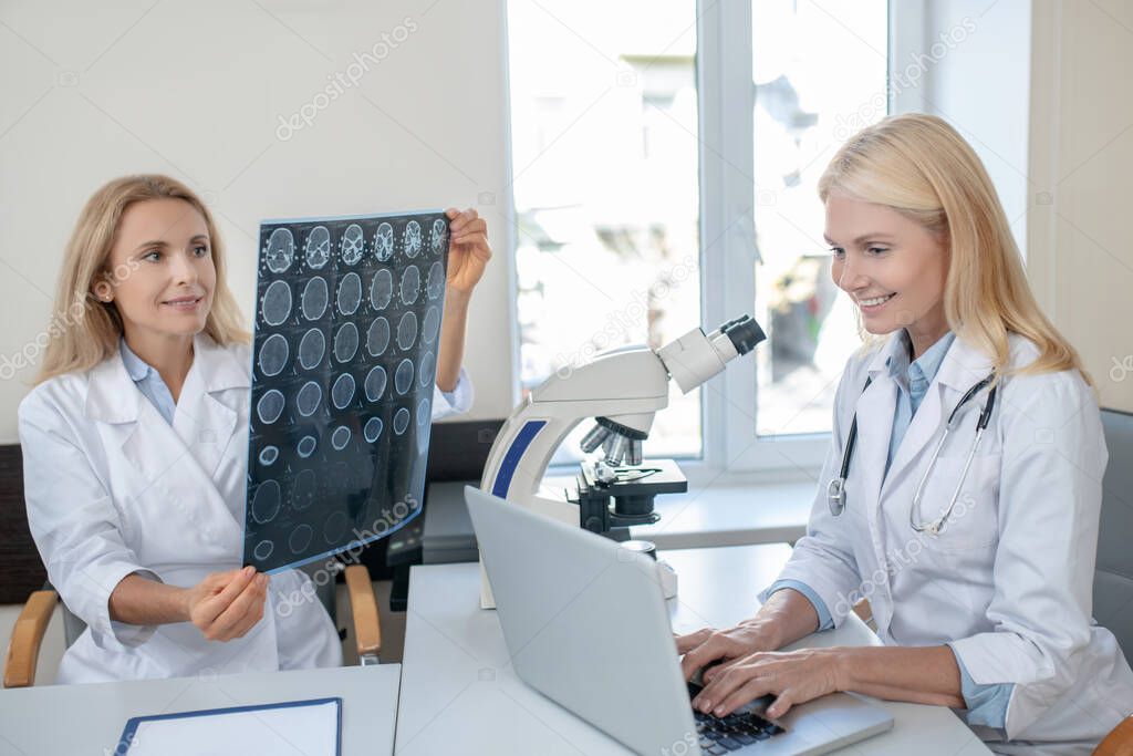 Two women in medical gowns are busy in office