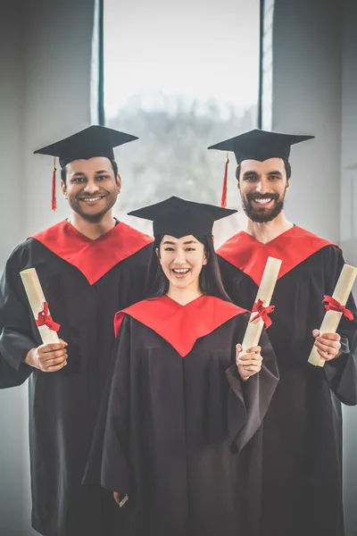 Graduates in mortarboards looking happy and joyful — Stock Photo, Image
