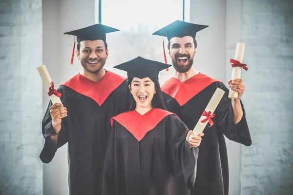 Graduados em morteiros que parecem felizes e alegres — Fotografia de Stock