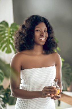 Elinde gerekli yağlarla sevimli esmer tenli genç bir kadın.