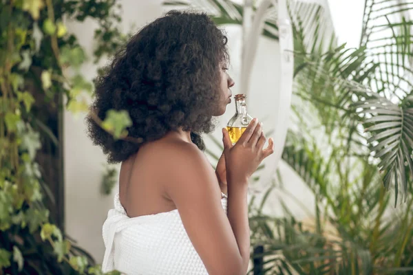 Leuke donkere jonge vrouw met etherische oliën in de hand — Stockfoto