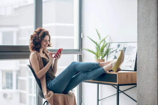 Mujer morena sentada con teléfono en las manos — Foto de Stock