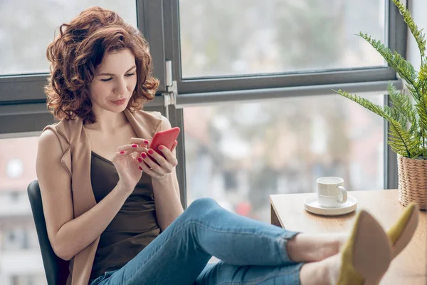 Mujer morena sentada con teléfono en las manos — Foto de Stock