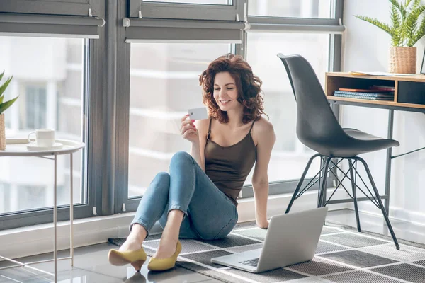 Темноволоса красива жінка працює на ноутбуці і виглядає задоволеною — стокове фото